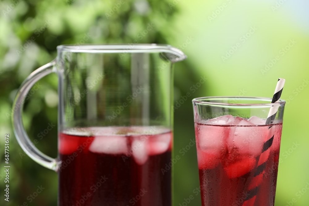 Refreshing hibiscus tea with ice cubes on blurred green background, closeup Refreshing hibiscus tea with ice cubes on blurred green background, closeup