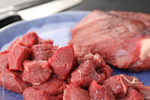 Plate with pieces of raw beef meat on table, closeup