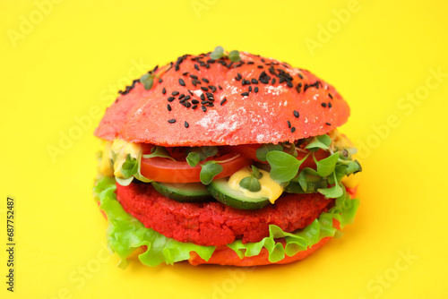 Tasty pink vegan burger with vegetables, patty and microgreens on yellow background, closeup