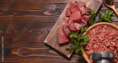 Manual meat grinder, beef, peppercorns and parsley on wooden table, flat lay. Banner design with space for text photo