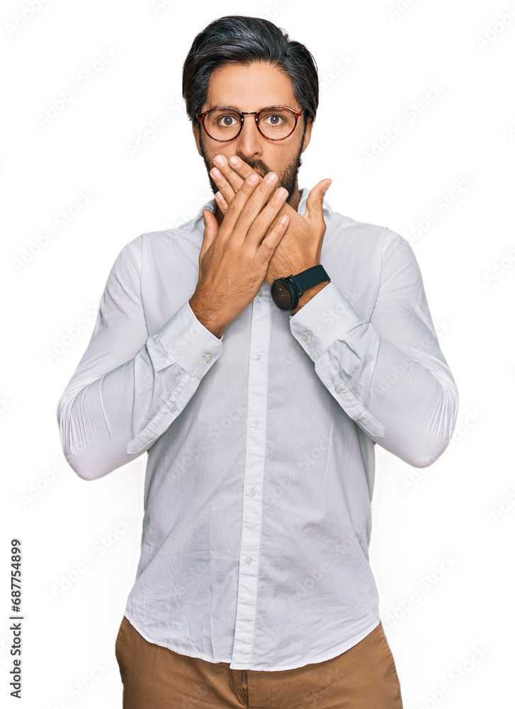 Young hispanic man wearing business shirt and glasses shocked covering mouth with hands for mistake. secret concept. Young hispanic man wearing business shirt and glasses shocked covering mouth with hands for mistake. secret concept.