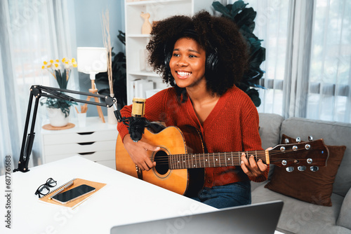 Host channel of beautiful African woman influencer singing with playing guitar in broadcast studio. Time slot of music blogger on live social media online. Concept of audio creator. Tastemaker. photo