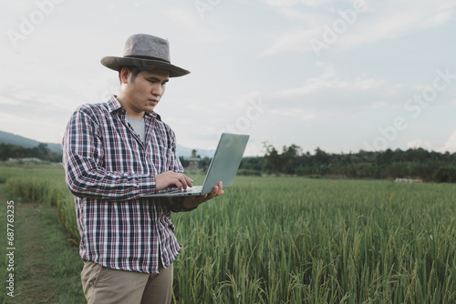A man farmer examines the field of cereals and sends data to the cloud from the tablet, Smart farming and digital agriculture, young farmer works with a laptop in a wheat field.