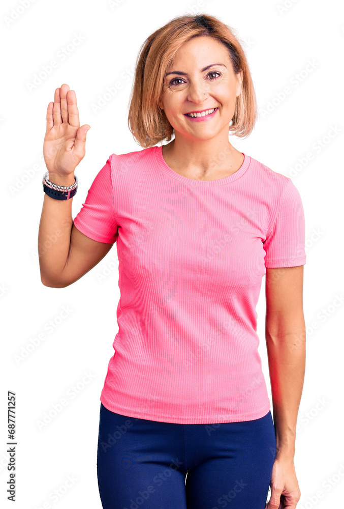 Young blonde woman wearing sportswear waiving saying hello happy and smiling, friendly welcome gesture Young blonde woman wearing sportswear waiving saying hello happy and smiling, friendly welcome gesture