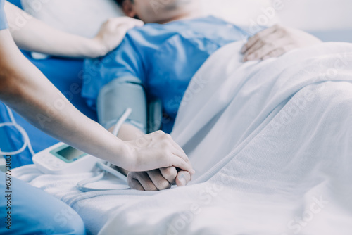 Side view of diverse doctors examining Asian female patient in bed in ward at hospital.