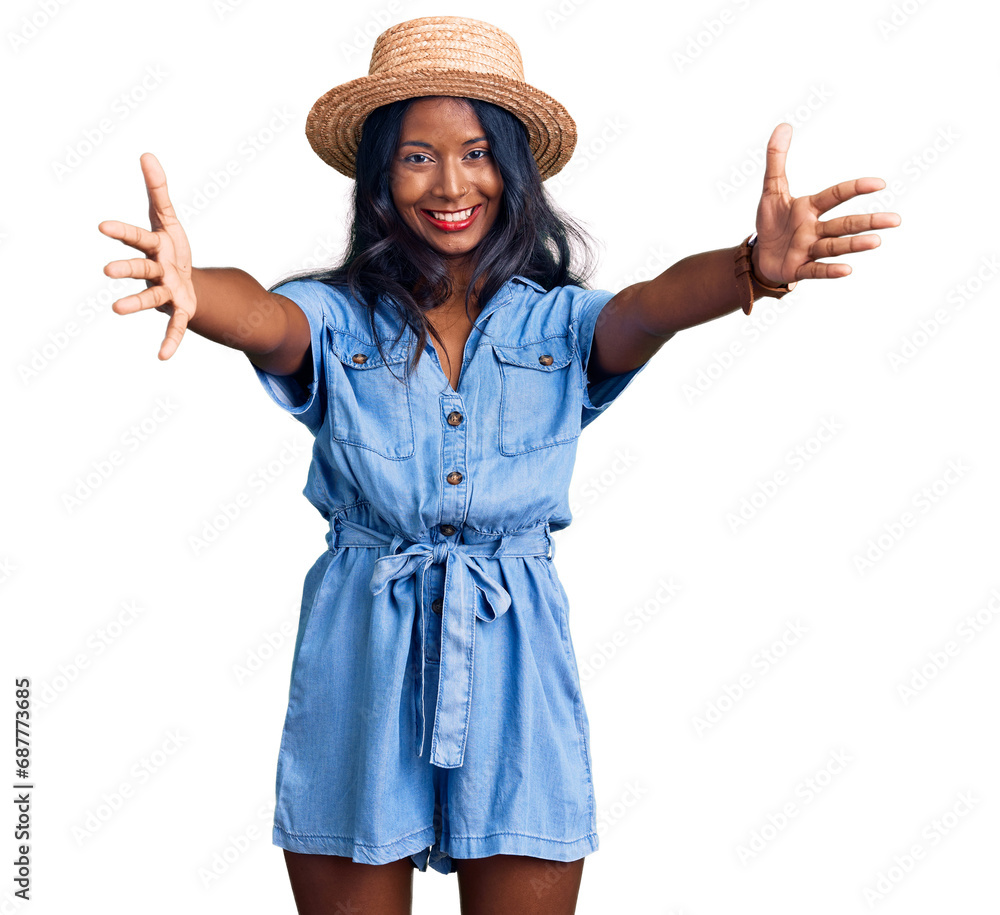 Young indian girl wearing summer hat looking at the camera smiling with open arms for hug. cheerful expression embracing happiness. Young indian girl wearing summer hat looking at the camera smiling with open arms for hug. cheerful expression embracing happiness.