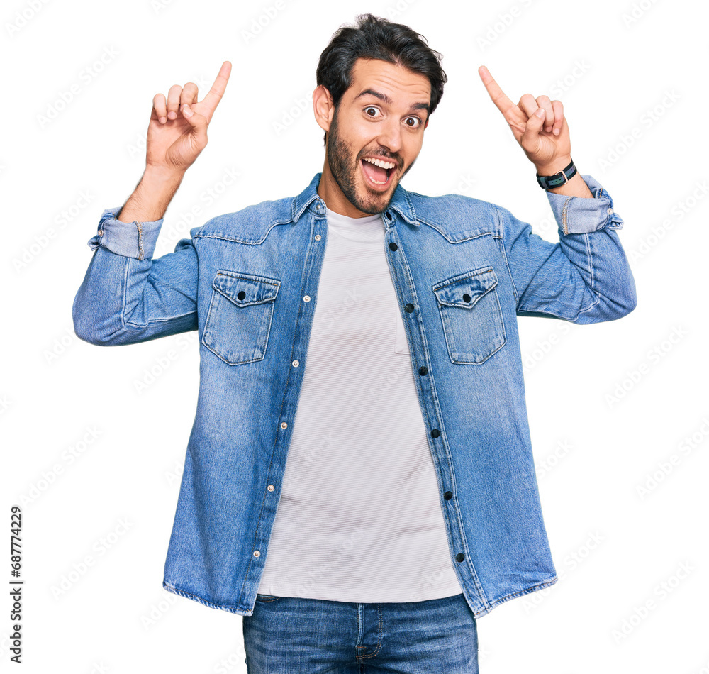 Young hispanic man wearing casual clothes smiling amazed and surprised and pointing up with fingers and raised arms. Young hispanic man wearing casual clothes smiling amazed and surprised and pointing up with fingers and raised arms.