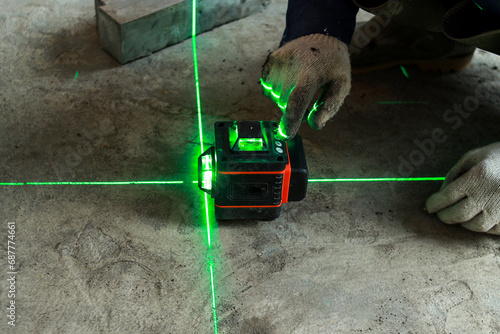Worker wear glove and checks the floor level with a laser level meter on the cement walls in construction site. photo