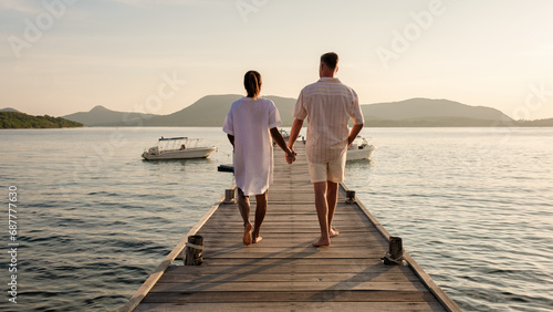 A couple at a wooden pier in the ocean during sunset in Samaesan Thailand photo