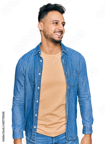 Young arab man wearing casual clothes looking away to side with smile on face, natural expression. laughing confident.