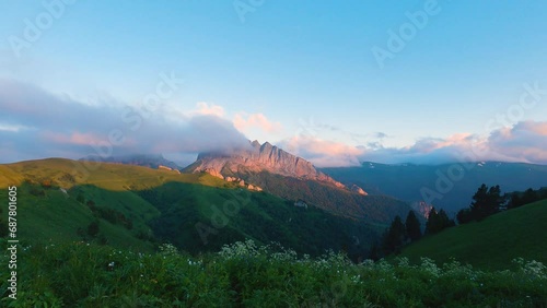 View of beautiful cliffs in the sunset light. A cloud covers part of the cliff. In the far background, snow-capped mountains with clouds hanging over them. Panoramic view of the mountains photo