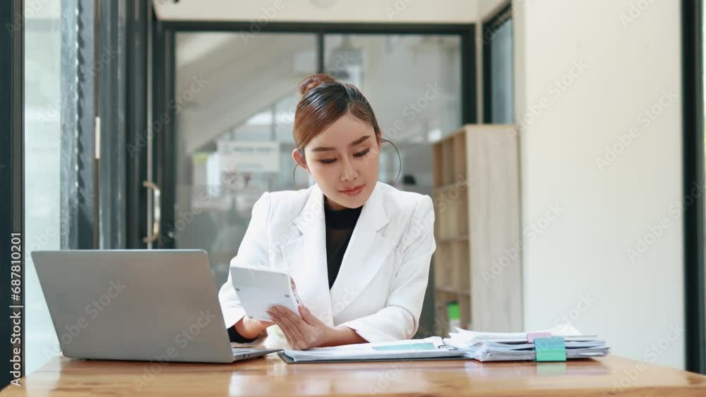 Asian woman sitting in a corporate office, business woman working, finance and accounting employees preparing financial statements, money management of a startup company. Asian woman sitting in a corporate office, business woman working, finance and accounting employees preparing financial statements, money management of a startup company.