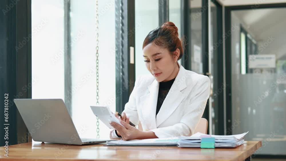 Asian woman sitting in a corporate office, business woman working, finance and accounting employees preparing financial statements, money management of a startup company. Asian woman sitting in a corporate office, business woman working, finance and accounting employees preparing financial statements, money management of a startup company.