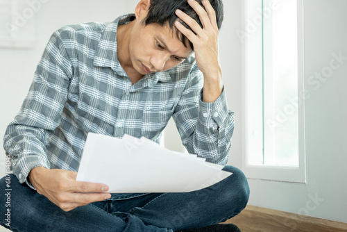 Stressed and headache asian man with large bills or invoices no money to pay to expenses and credit card debt. shortage, Financial problems, mortgage, loan, bankruptcy, bankrupt, poor, empty wallet.