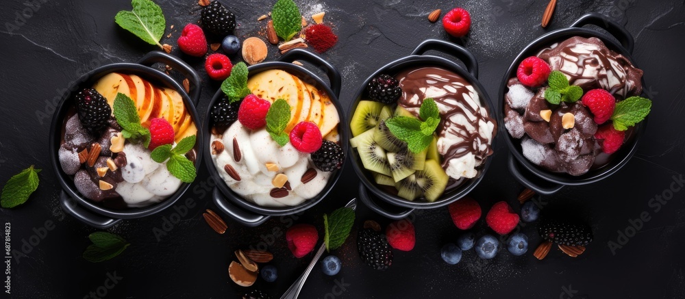 Fresh fruit tubs with ice cream, chocolate, berries, nuts, scoop, on slate, top view, copy space.