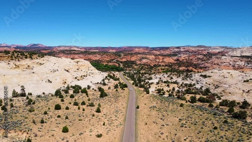 single white car driving towards camera in Utah desert landscape, sunny mountain highway route in USA photo