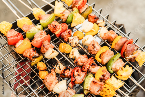 Grilled skewers with meat and colorful vegetables on a BBQ grill, showing charred marks, ready for a delicious meal.