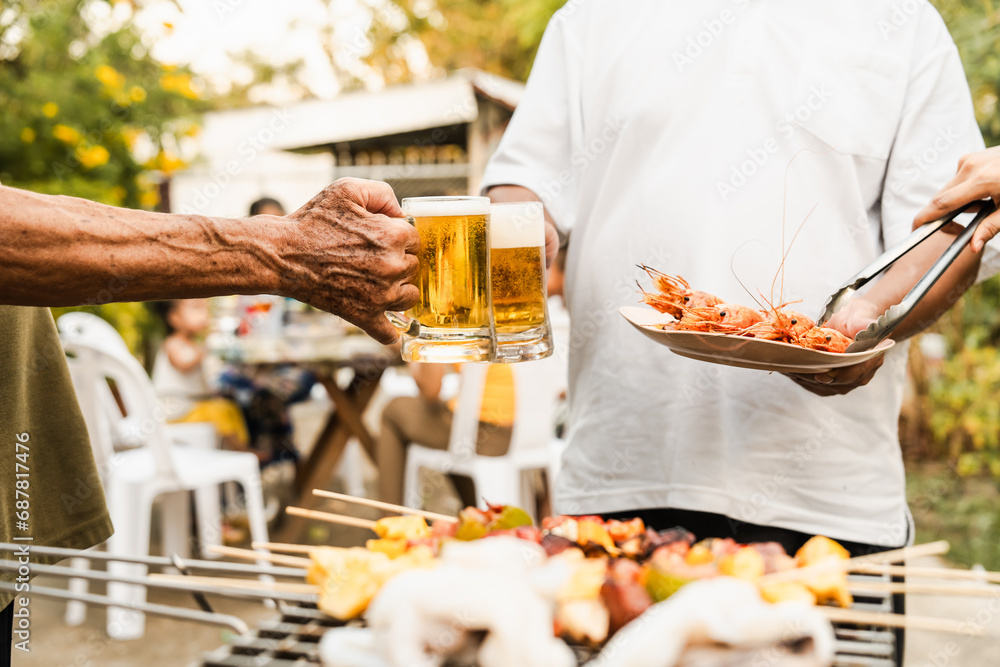 Outdoor barbecue with various meats on grill, two people holding plates and drinks, smoke rising, festive and casual atmosphere. holding glass of beer. family party. Outdoor barbecue with various meats on grill, two people holding plates and drinks, smoke rising, festive and casual atmosphere. holding glass of beer. family party.
