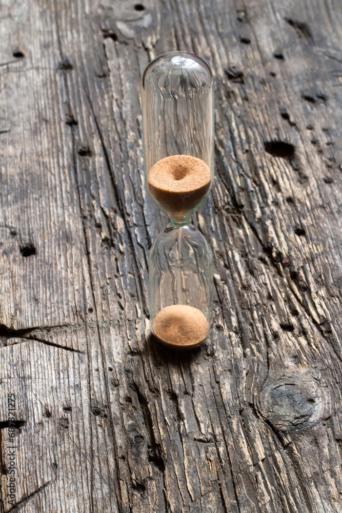 Hourglass on old wood. The passage of time. Close-up of glass hourglass.