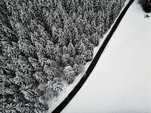 Empty winter road in snow covered forest, top down aerial drone photo, Black Forest, Baiersbronn, Germany