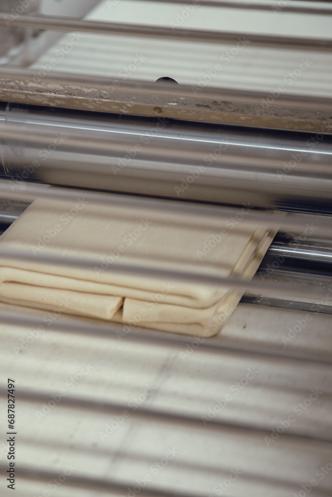 Close up of croissant dough going through the rolling machine. Artisan bakery. In the kitchen. Close up of croissant dough going through the rolling machine. Artisan bakery. In the kitchen.