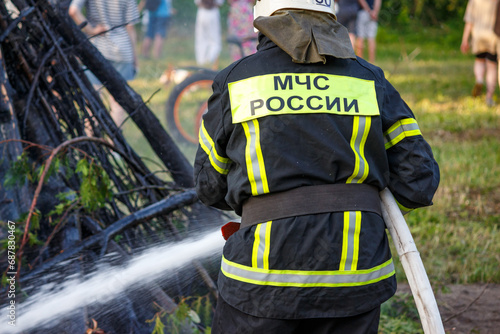 The inscription of the Ministry of Emergency Situations of Russia on the uniform of a firefighter who puts out a fire. Russia photo
