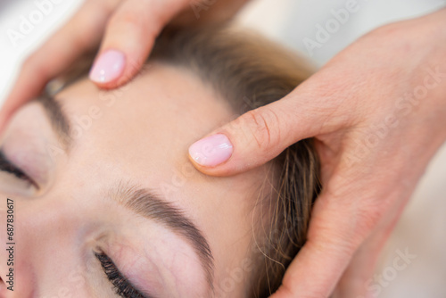 Close up view of healer hands performing by lightly touched access bars therapy on young woman head, stimulating positive change thoughts and emotions in salon. Alternative medicine concept