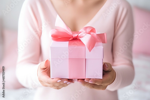 Woman hands holding a pink valentine gift present box with pink ribbon © Keitma