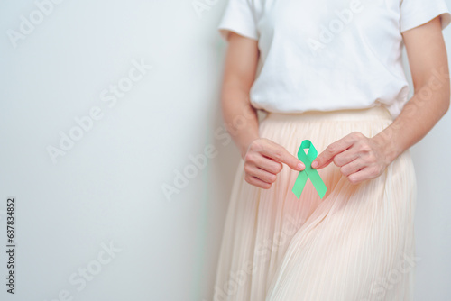 Woman holding Teal Ribbon on abdomen for January Cervical Cancer Awareness month. Uterus and Ovaries, Cervix, Endometriosis, Hysterectomy, Uterine fibroids, Reproductive and World cancer day concept photo