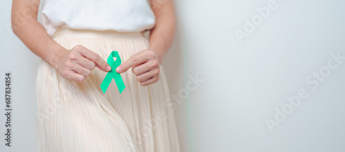 Woman holding Teal Ribbon on abdomen for January Cervical Cancer Awareness month. Uterus and Ovaries, Cervix, Endometriosis, Hysterectomy, Uterine fibroids, Reproductive and World cancer day concept photo