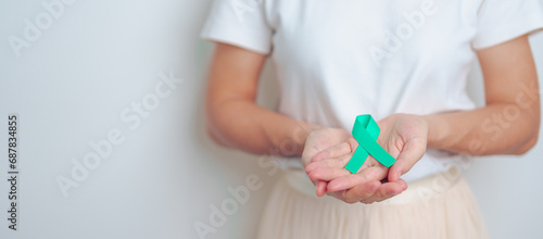 woman holding Teal Ribbon for January Cervical Cancer Awareness month. Uterus and Ovaries, Cervix, Endometriosis, Hysterectomy, Uterine fibroids, Reproductive, Healthcare and World cancer day photo