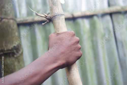 A man is holding dry bamboo with his hands and blurred background © Rokonuzzamnan