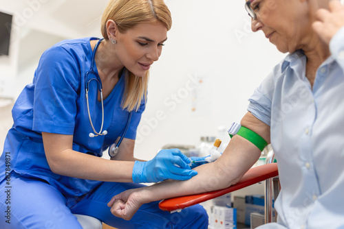 Preparation for blood test with senior woman by female doctor medical uniform on the table in white bright room. Nurse pierces the patient's arm vein with needle blank tube. photo