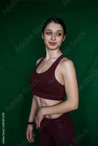 Portrait of young caucasian woman in sports outfit isolated on green