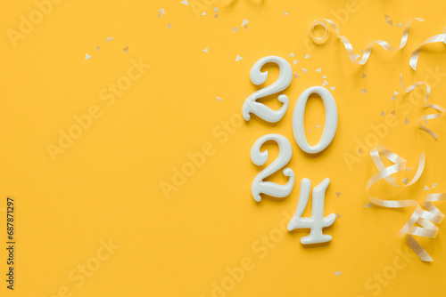 close up year of 2024 shape wood on yellow color background with white rolling ribbon and glitter confetti for countdown and template banner design ads concept