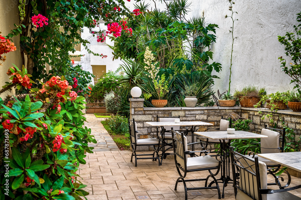 A charming backyard café emerges within a lush green oasis, offering a serene retreat with a few inviting tables and chairs surrounded by vibrant foliage. Perfect for use in travel blogs, hospitality 