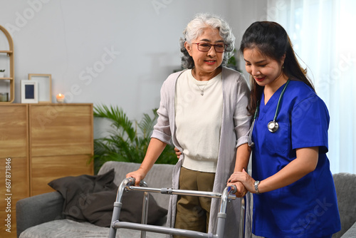 Female nurse helping senior woman to walking in her home with walker