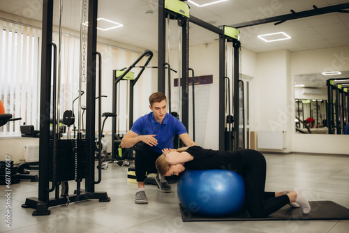 man and woman wearing physiotherapist uniform having rehab session using fit ball at rehab center