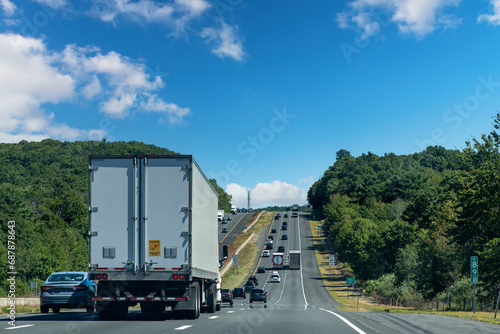 Drivers perspective view over busy and hilly Interstate 84 highway in northerly direction near Willington, CT, USA with trucks and cars on highway
