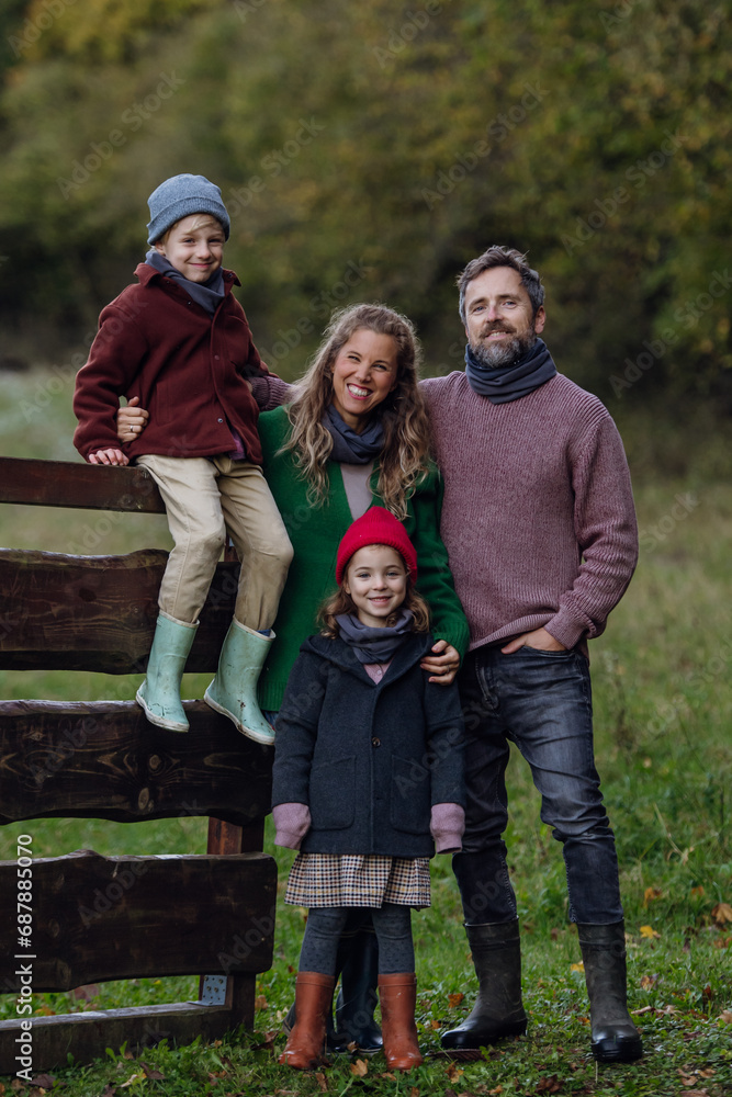Portrait of family outdoors going on walk in nature. Mother, father and kids spending time outdoors during cold autumn day.