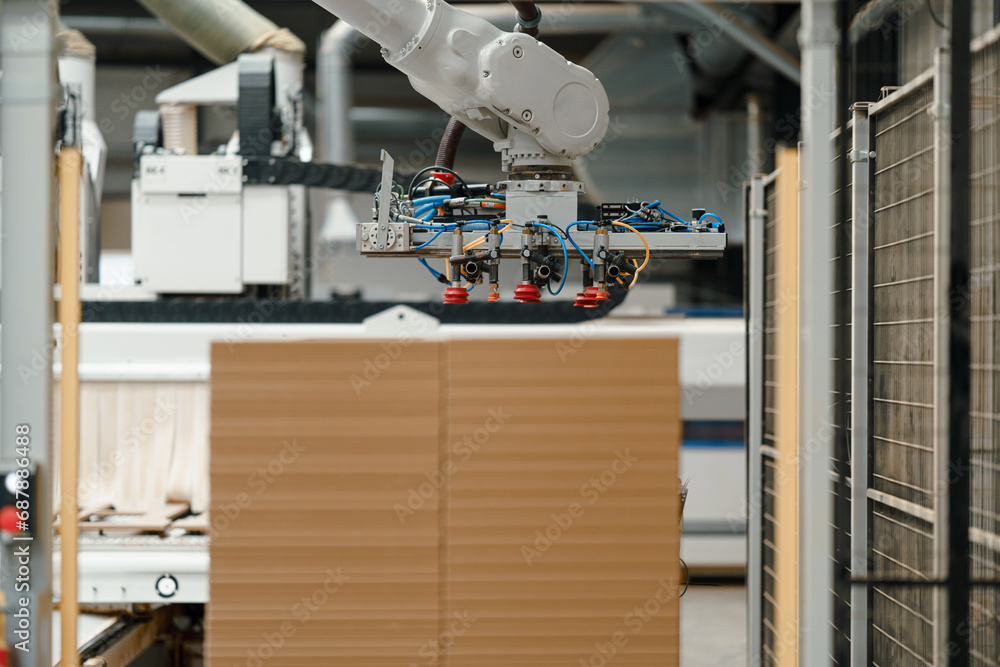 Naklejka premium Close up of robotic arm in modern industrial factory, production of wooden furniture. Big furniture manufacturing facility with robotics and automation.