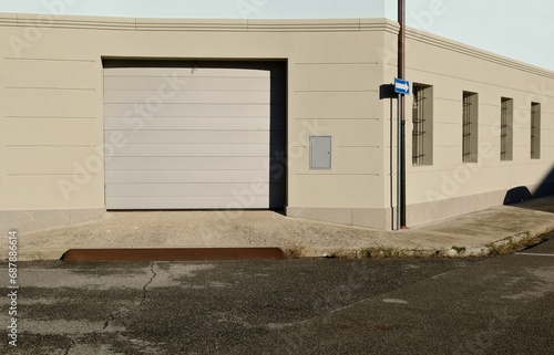 Modern gray electric garage door at the roadside with street in front. Directional arrow sign,sidewalk and row of windows on the right. Background for copy space. photo