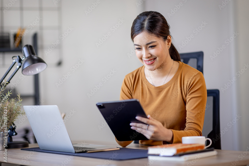 Young modern business asian woman working using digital tablet while sitting in the home office Young modern business asian woman working using digital tablet while sitting in the home office