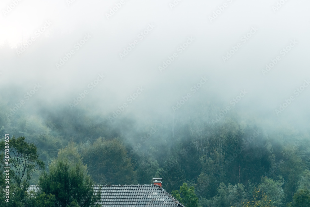 Fog clouds over a mountain house in slovenian Julian Alps forest landscape Fog clouds over a mountain house in slovenian Julian Alps forest landscape