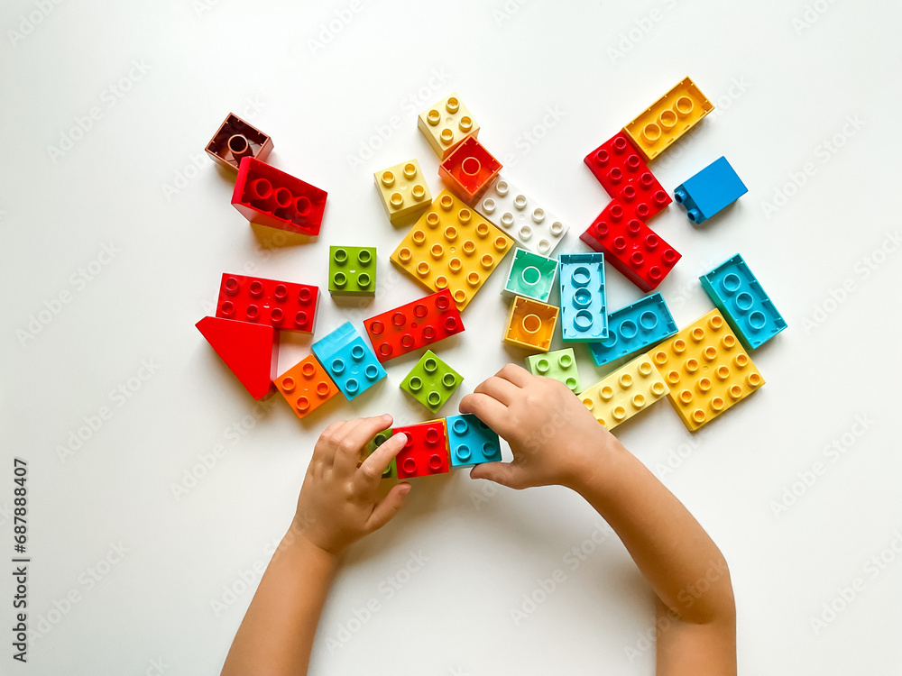 Child playing with colorful building blocks on a white background. Top view Child playing with colorful building blocks on a white background. Top view