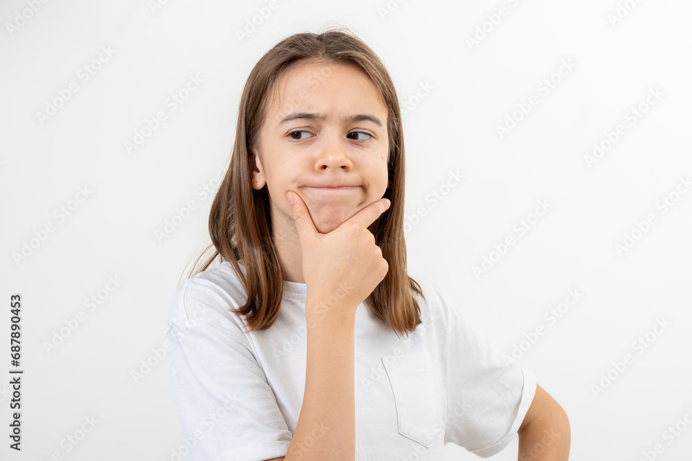 A schoolgirl thoughtfully holds her hand near her face on a white background. A schoolgirl thoughtfully holds her hand near her face on a white background.