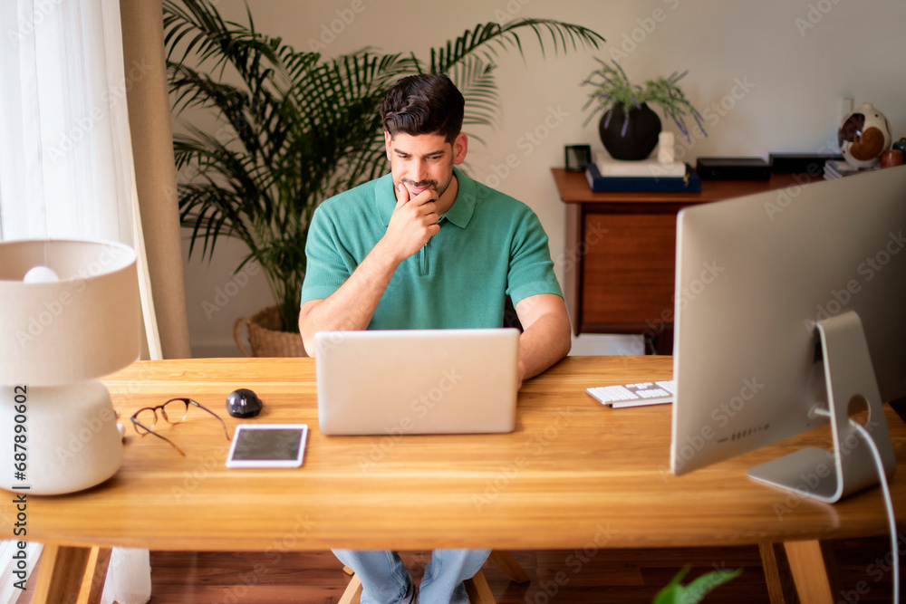 Mid aged businessman with laptop sitting at desk and working at home Mid aged businessman with laptop sitting at desk and working at home