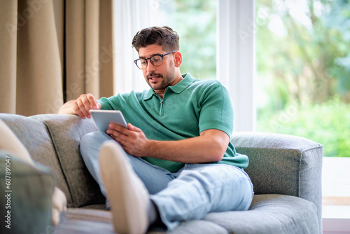 Mid aged man sitting at home and using digital tablet