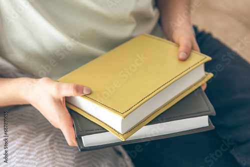 A woman sits on the sofa and holds books, close-up.