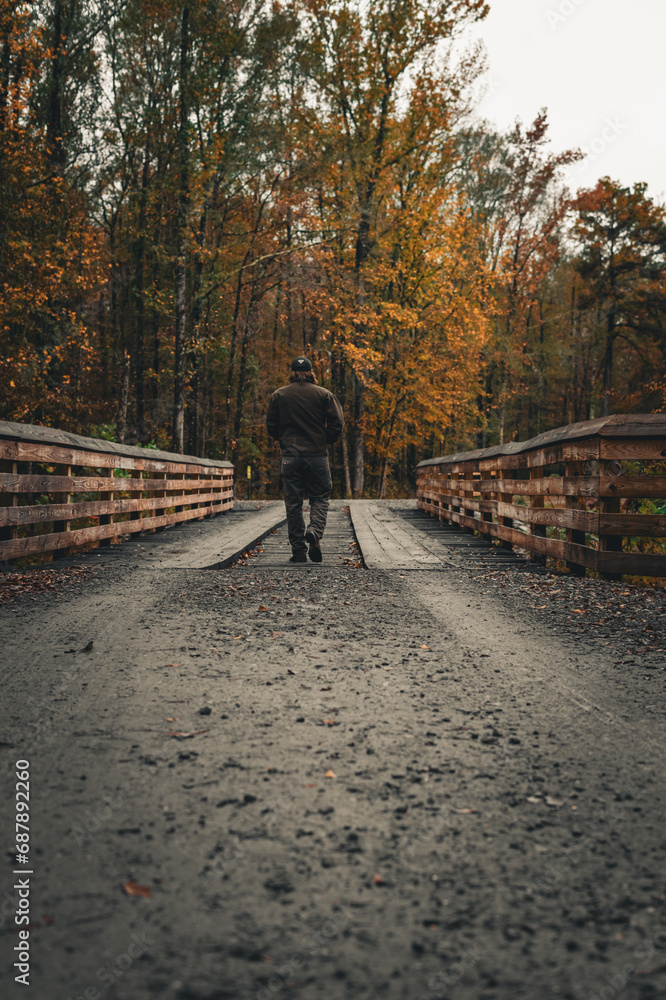 Guy walking over wood bridge